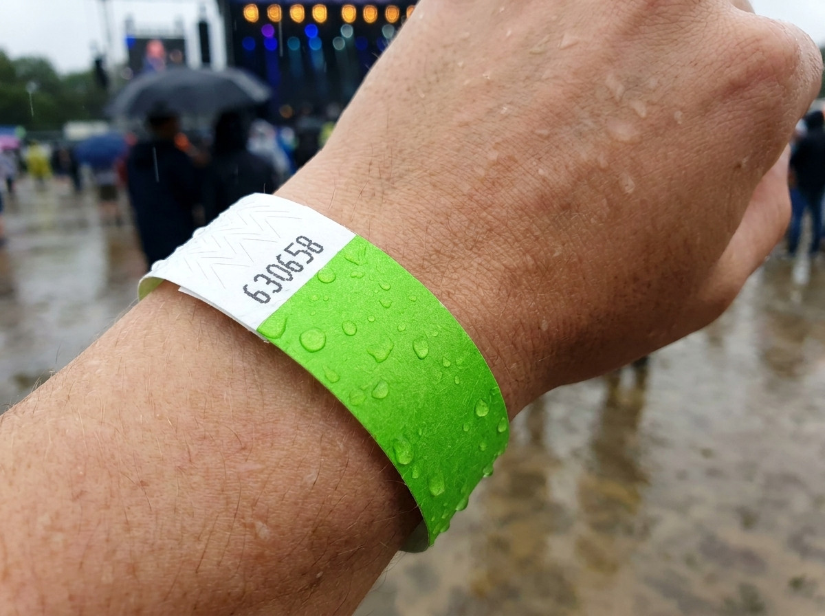 Identificatiearmband gedragen om de pols in de regen tijdens een openluchtfestival, ter illustratie van de water- en vochtbestendigheid