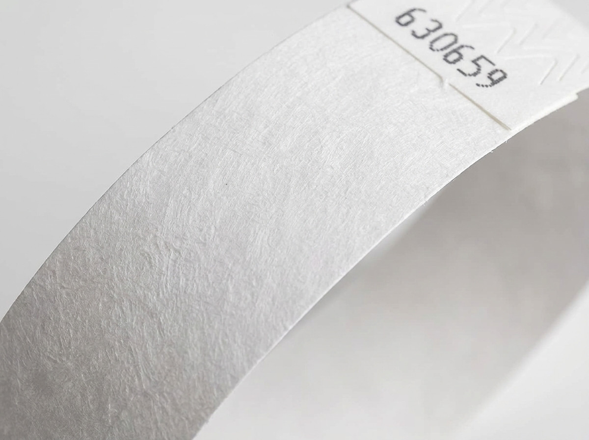 Close-up van het niet-geweven oppervlak van een wit Tyvek polsbandje, met de kenmerkende textuur van hogedichtheid polyethyleen